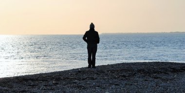 Siluet adam çakıl taşı plajı fotokopi uzayı ile macerayı keşfetmek için tek başına