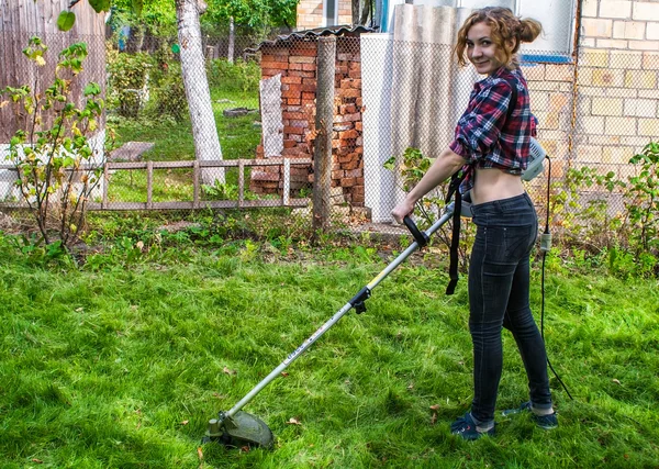 Vrouw in plaid shirt maaien gazon — Stockfoto