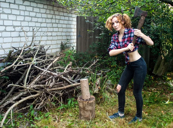 Ernste Frau hackt Holz Stockfoto