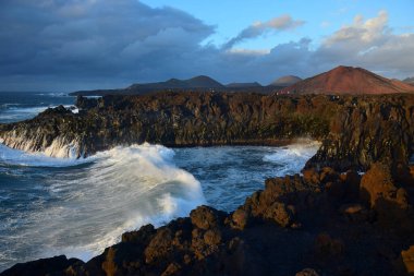 Los Hervideros, Lanzarote 'un batı kıyısında akşam güneşinde. Yüksek dalgalar geliyor. Kanarya Adaları, İspanya.