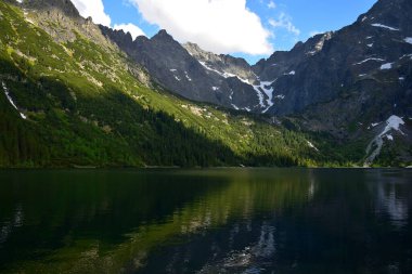 Morskie Gölü, Denizin Gözü olarak da bilinir, orman ve dağlarla çevrilidir. Yüksek Tatras, Polonya. Altın saat.