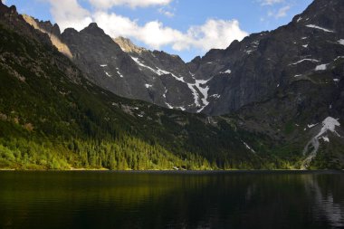 Morskie Gölü, Denizin Gözü olarak da bilinir, orman ve dağlarla çevrilidir. Yüksek Tatras, Polonya. Altın saat.