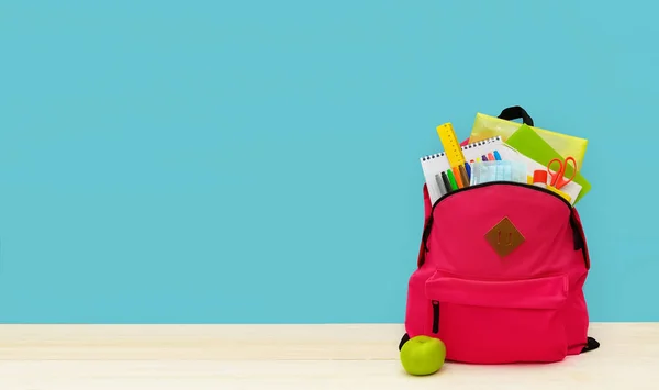 Back to school. Backpack for school or college with bright colorful school supplies on blue background. Stationery for school children's studies. Greeting card or banner for sale. Copyspace. Mock up