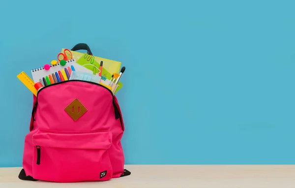 Back to school. Backpack for school or college with bright colorful school supplies on blue background. Stationery for school children's studies. Greeting card or banner for sale. Copyspace. mock up