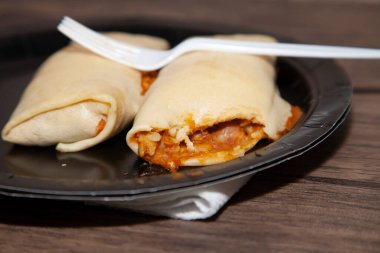 Siyah tabakta fasulye, peynir ve pirinç dürümleri.