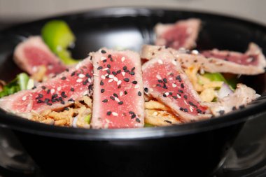 Marullu kurutulmuş ton balığı salatası, dilimlenmiş yeşil dolma biber ve ahşap masada kırmızı soğan.