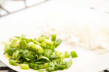 Beyaz tabakta doğranmış yeşil soğan ve doğranmış beyaz soğan.