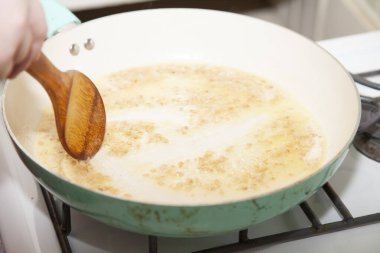 Sos yapmak için tereyağına doğranmış sarımsak karıştırmak.