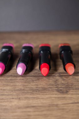 Ahşap tezgahta dört pembe ve kırmızı ruj.