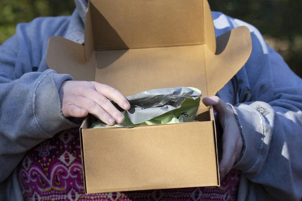 Žena Otevírá Zelený Igelitový Sáček Kartonové Krabici — Stock fotografie