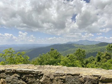 Dağların, ağaçların ve bulutların görüntüsü insan yapımı taş bir çıkıntıdan