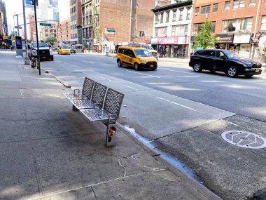 New York, New York, ABD - 6 Temmuz 2021: Altıncı Cadde 'deki kaldırımda demirli metal bir bank