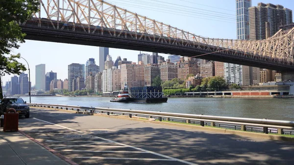 Roosevelt Adası, New York, ABD - 19 Temmuz 2021 Queensboro Köprüsü 'nün altından römorkör geçiyor