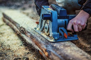 İnşaatçının eline tahta kesmek için dairesel testere. Parmaklıkları, inşaatı, tadilatı ve inşaat aletlerini kesmiş. Marangoz tahta için testere kullanıyor. Yakın plan.
