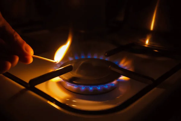 Gas burner on white modern kitchen stove. Kitchen gas cooker with burning fire propane gas. A man lighting the gas-stove with a match.