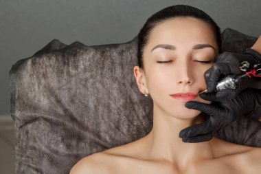 Kalıcı makyaj prosedürü, genç bir kıza uygulanacak. Yakın plan. Kozmetik salonunda kalıcı makyaj yapan güzel bir kadın.