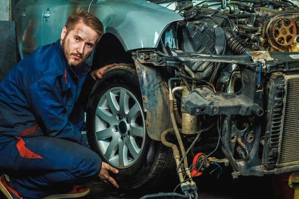 Serviceman checking suspension in a car at garage. Mechanic repaired wheeled vehicles. Mechanic Holding Car Tire At Garage. Mechanician changing car wheel in auto repair shop. Change a flat car tire on road with Tire maintenance, damaged car tyre.