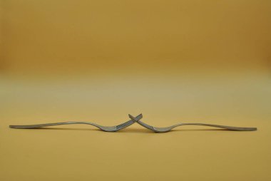 Nötr turuncu arkaplan üzerine izole edilmiş iki iç içe geçmiş çatalın bileşimi