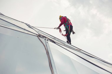 Erkek işçiler halatla yükseklik güvenliğine bağlanıyor 8 knot emniyet kemerine bağlanıyor, çatıya bağlanıyor, düşüş tutuklaması ve düşme demirleme noktası sistemleri yükselmeye hazır, inşaat alanı petrol tankı kubbesi.