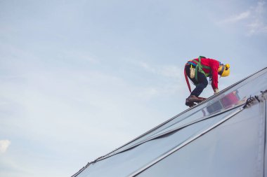 Erkek işçiler halatla yükseklik güvenliğine bağlanıyor 8 knot emniyet kemerine bağlanıyor, çatıya bağlanıyor, düşüş tutuklaması ve düşme demirleme noktası sistemleri yükselmeye hazır, inşaat alanı petrol tankı kubbesi.