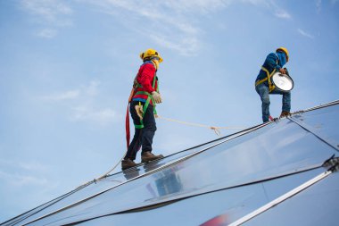 İki erkek işçi halat erişim yüksekliği 8 knot emniyet kemerine bağlanıyor, çatıya bağlanıyor, düşüş tutuklaması ve yükselmeye hazır çapa noktası sistemleri, inşaat alanı petrol tankı kubbesi.