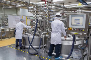 İkinci erkek, arka planda paslanmaz tankla birlikte üretimde krem kozmetik fermantasyonu üzerinde çalışıyor.