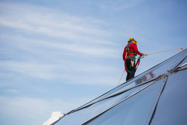 Male workers rope access height safety connecting with eight knots safety harness, clipping into roof fall arrest and fall restraint anchor point systems ready to ascending, construction site oil tank dome.