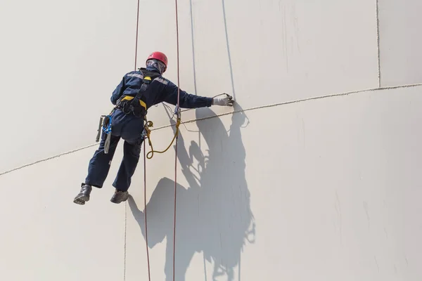 Male worker rope access  inspection of thickness storage tank industry.