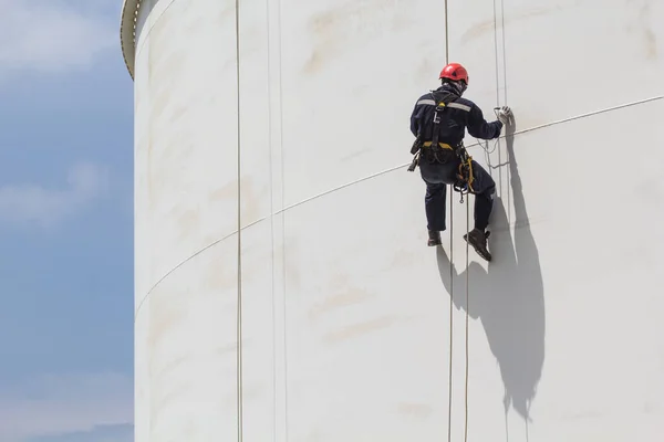 Male worker rope access  inspection of thickness  white storage tank  shadow industry oil