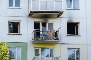 Bir apartmanda yangın çıkmış. Yanmış bir apartmanın açık, kırık camları, binanın ön cephesinde is..