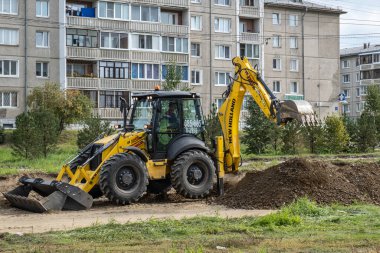 RUSSIA, ANGARSK - 08 Eylül 2020 İnşaat, şehrin yerleşim alanındaki bir yolun onarımı. Yol yapım makineleri yeni asfalt yüzeyi için yolun bir bölümünü temizliyor.