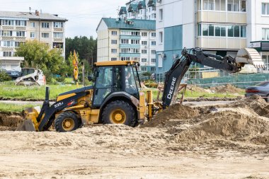 RUSSIA, ANGARSK - 08 Eylül 2020 İnşaat, şehrin yerleşim alanındaki bir yolun onarımı. Yol yapım makineleri yeni asfalt yüzeyi için yolun bir bölümünü temizliyor.