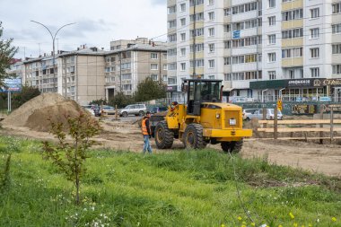 RUSSIA, ANGARSK - 08 Eylül 2020 İnşaat, şehrin yerleşim alanındaki bir yolun onarımı. Yol yapım makineleri yeni asfalt yüzeyi için yolun bir bölümünü temizliyor.
