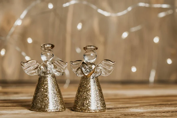 Tahta bir arka planda iki melek ve bir çelenk olan Noel kartı. Odaklanmamış ışıklar arka plan ve Noel süslemeleri. Seçici odak.