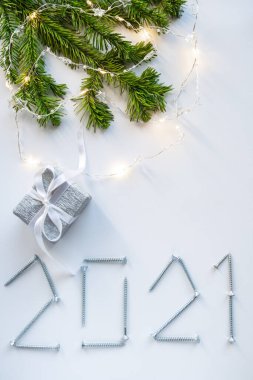 Beyaz arka plandaki vidalardan yapılmış yaratıcı bir Noel kartı. Hediye ve filizle birlikte. Yeni yılın yaratıcı konsepti.