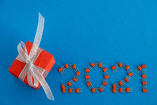 Yaratıcı Noel kartı. Kırmızı paketli mavi arka plandaki transistörlerden 2021. Yeni yılın yaratıcı konsepti. Boşluğu kopyala.