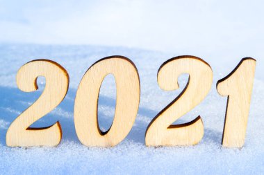 2021 yılını kutluyoruz. 2021 numaralı ahşap, karlı ve doğal bir yüzeyde. Parlak güneşin altında. Doğal stil.