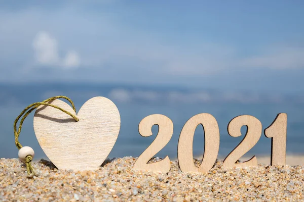 Yaratıcı Noel kartı. 2021 numara plajda gökyüzüne karşı kalplerle. Turizm ve eğlence konsepti. Seçici odaklanma. Boşluğu kopyala.
