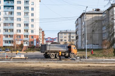 RUSSIA, ANGARSK - 17 Ekim 2020 İnşaat, şehrin yerleşim alanındaki bir yolun onarımı. Bir çöp kamyonu inşaat halindeki yeni bir yola moloz getiriyor..