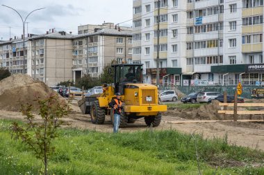 RUSSIA, ANGARSK - 08 Eylül 2020 İnşaat, şehrin yerleşim alanındaki bir yolun onarımı. Yol yapım makineleri yeni asfalt yüzeyi için yolun bir bölümünü temizliyor.
