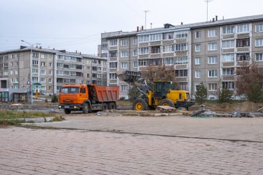 RUSSIA, ANGARSK - 19 Ekim 2020 İnşaat, şehrin yerleşim alanındaki bir yolun onarımı. Yol yapım makineleri inşaat için yolun bir bölümünü temizliyor.