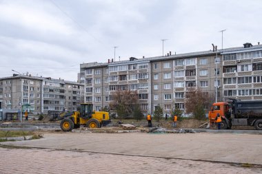 RUSSIA, ANGARSK - 19 Ekim 2020 İnşaat, şehrin yerleşim alanındaki bir yolun onarımı. Yeni bir yolun şantiyesinde işçiler ve yol yapım ekipmanları.