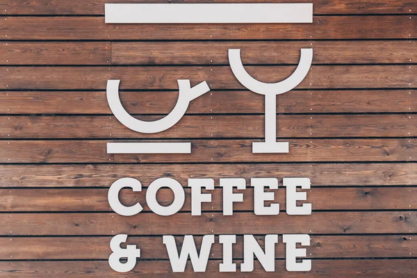 Stilisierte Tasse Kaffee und ein Glas Wein auf einem hölzernen Hintergrund. Die Worte Kaffee und Wein. Café-Aushängeschild — Stockfoto