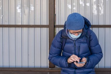 Tıbbi maskeli olgun bir adam sonbaharda toplu taşıma durağında oturur ve otobüs, tramvay ve tramvay bekler. Akıllı telefon kullanarak, toplu taşıma araçlarının yeri hakkında bilgi topluyor..