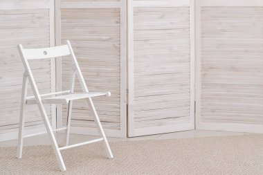 Ahşap bir ekranın arka planına karşı basit beyaz bir sandalye. Pastel renkler. Asgari tasarım