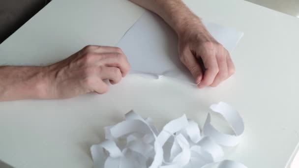 Gros plan des mains d'une personne nerveuse et malade qui déchire lentement le papier en lanières et les jette de côté. — Video