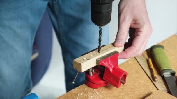 Primer plano de un hombre que trabaja con un taladro. Una persona experta hace agujeros en tablones de madera. — Vídeo de stock