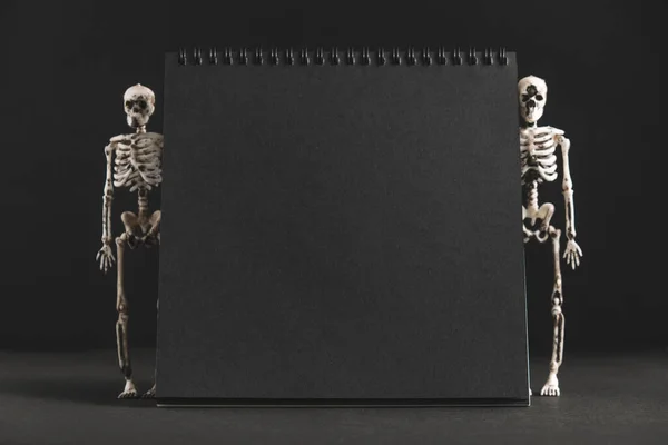 Pusty Czarny Notatnik Czarnym Tle Dwoma Szkieletami Bokach Minimalistyczny Projekt — Zdjęcie stockowe