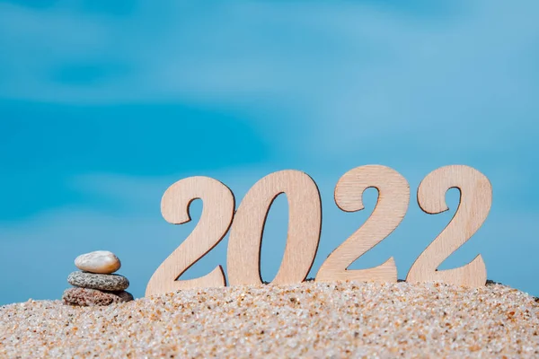 Yaratıcı Noel kartı. Deniz kıyısında 2022 yılbaşı sayısı, Cairn. Turizm, eğlence ve seyahat kavramı. Seçici odaklanma. Boşluğu kopyala.