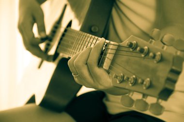 Kadın akustik gitar çalıyor.